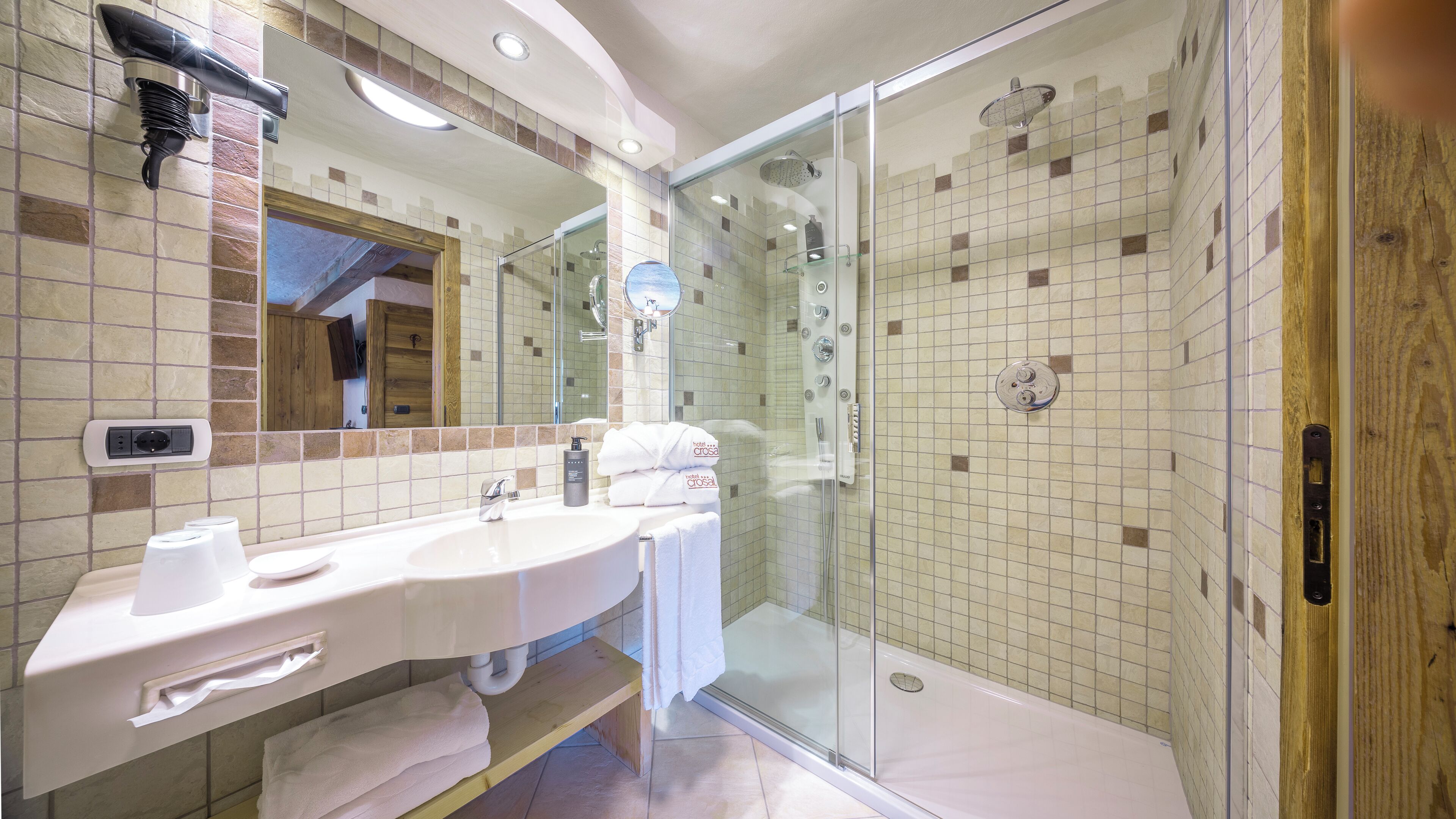A bathroom with a glass shower enclosure, a vanity with a mirror, and a towel rack.
