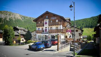 A hotel with a balcony, a sign reading "Hotel Croisal", and a view of a mountain.