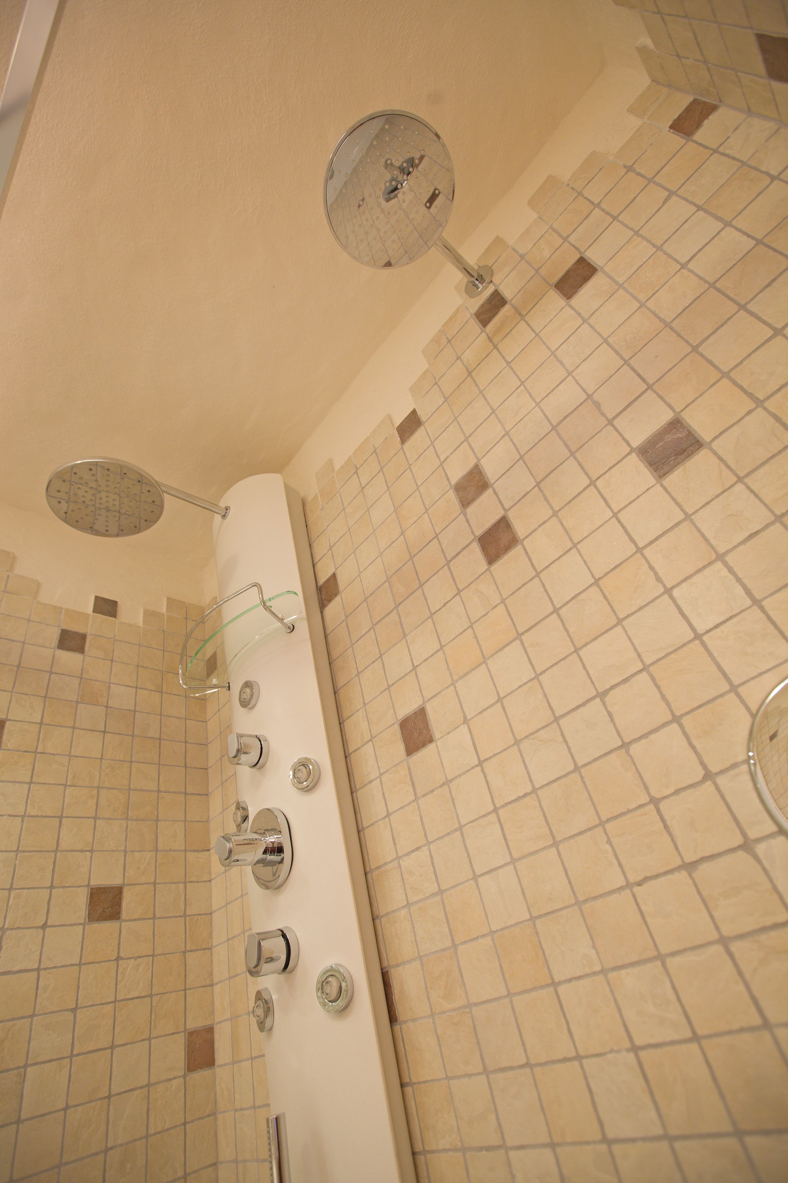 Un baño con ducha, espejo y pared con azulejos.