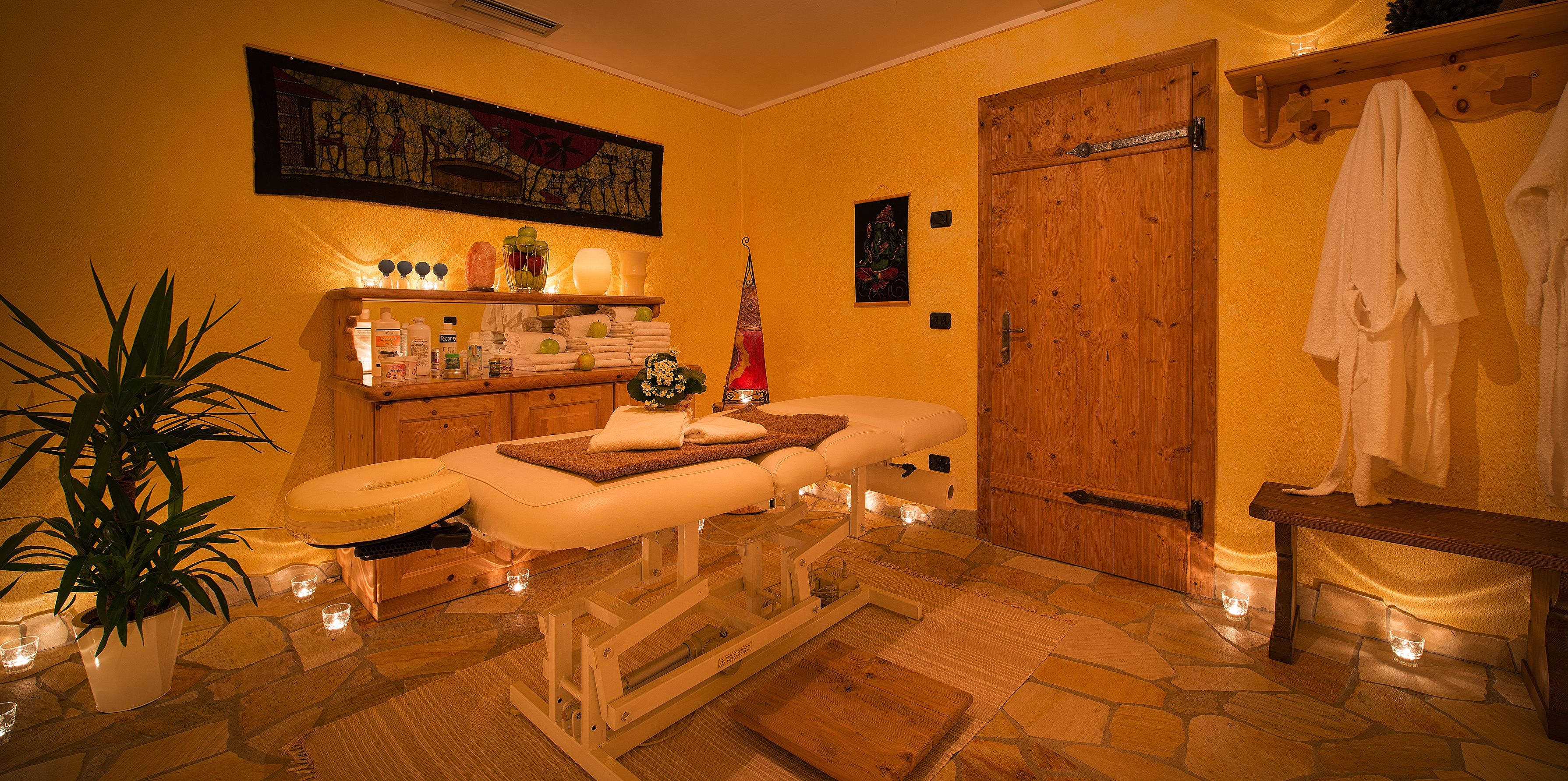 Un cuarto de spa con una camilla de masaje, una puerta de madera y un banco con toallas.