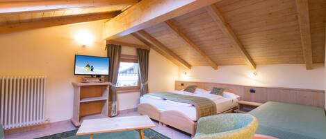 Una habitación acogedora con techo de madera, una cama, un escritorio, una silla y un televisor.