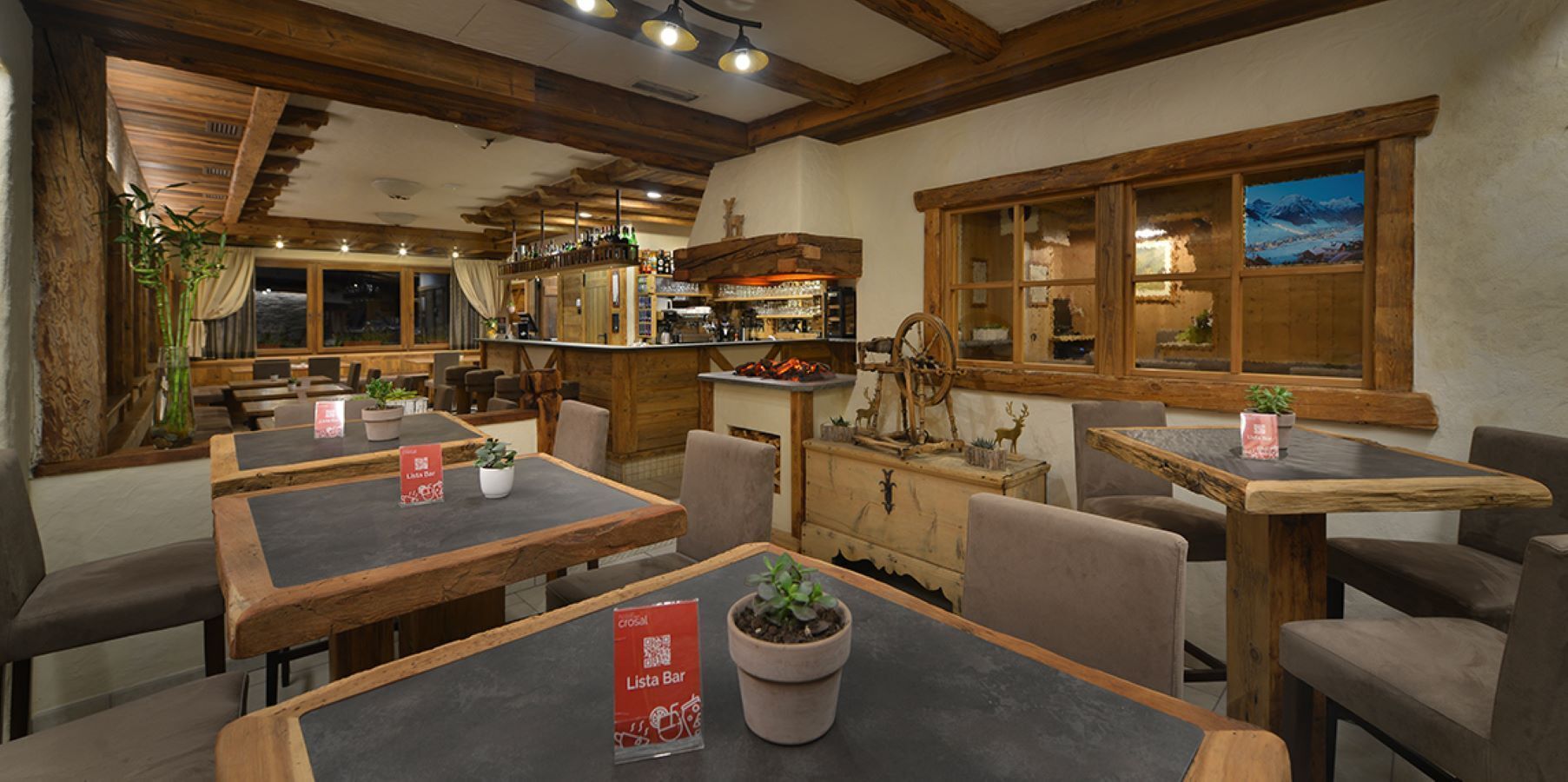 A rustic restaurant interior with wooden tables, chairs, and a bar area.