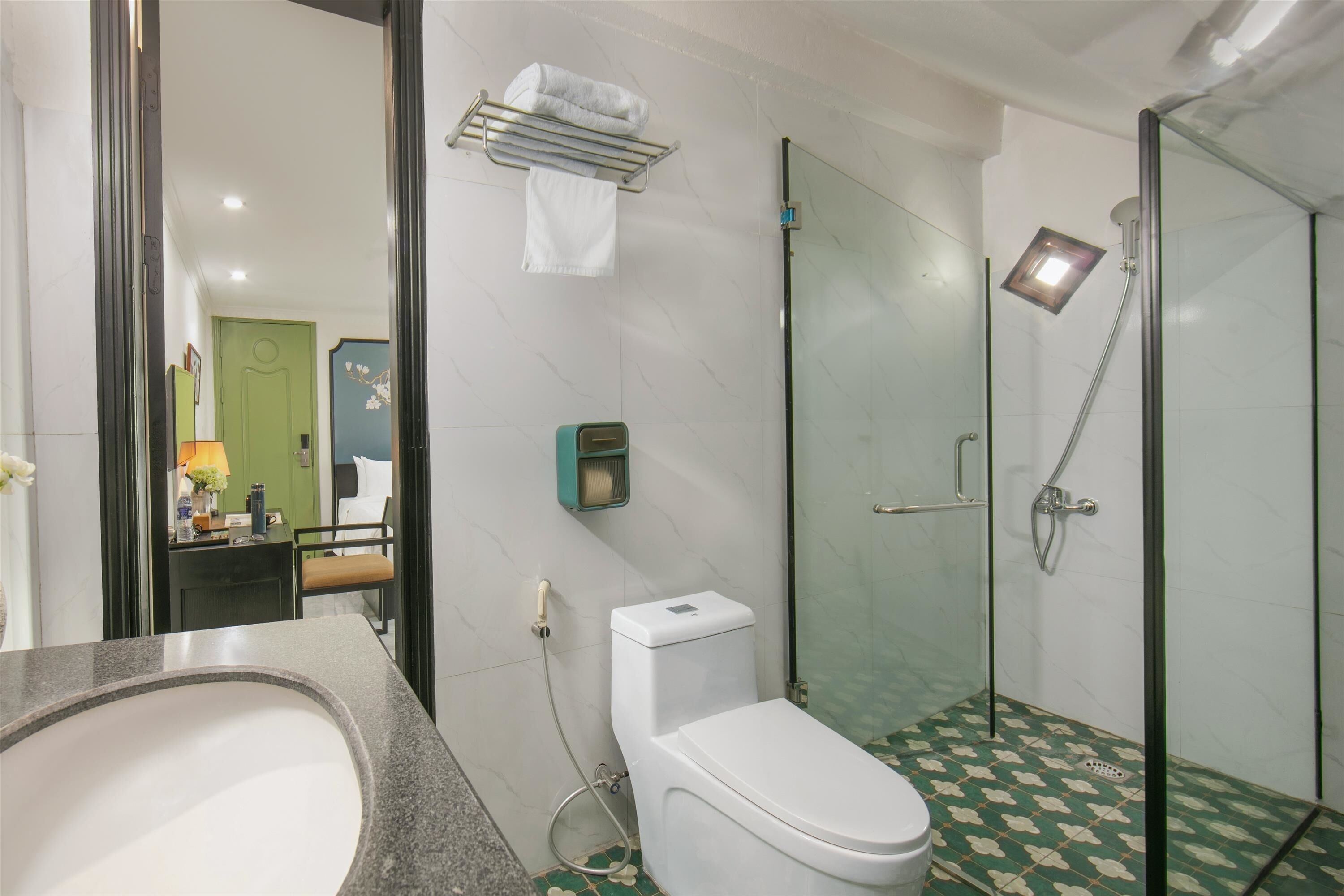 Une salle de bain équipée de toilettes, d’un lavabo et d’une douche à parois de verre.