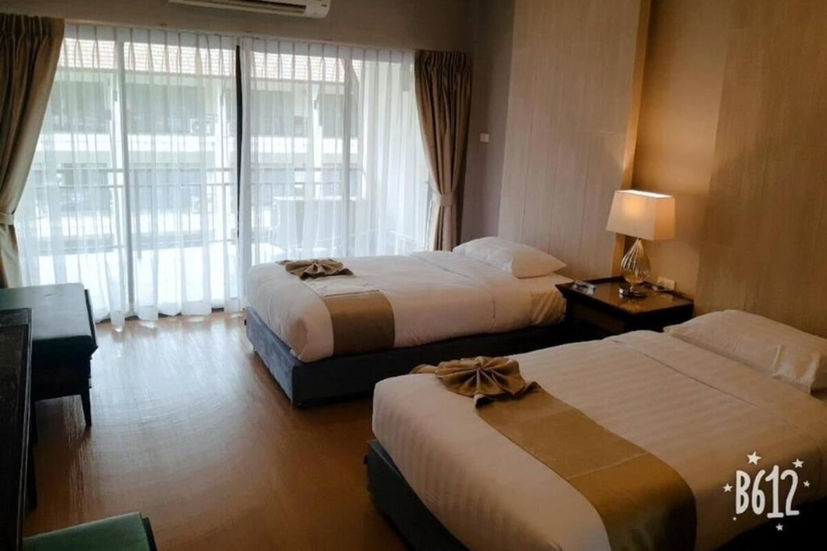 Quarto de hotel com duas camas, uma escrivaninha e um abajur.
