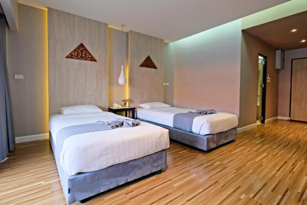Quarto de hotel com duas camas, piso de madeira e design moderno.