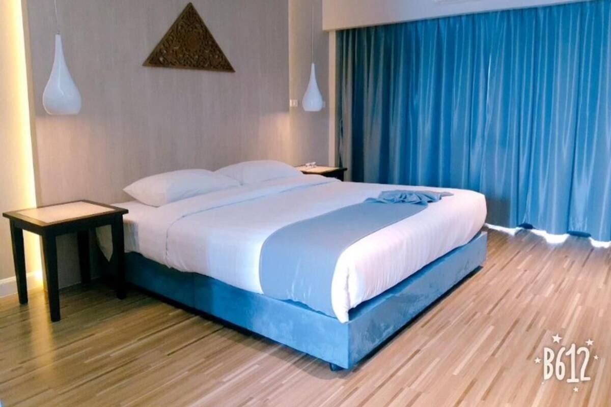 Quarto de hotel moderno com uma cama grande, mesa de cabeceira e ar condicionado fixado na parede.