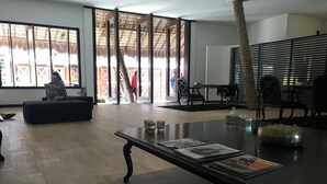 A spacious room with a large window, a black table with magazines, and a seating area with a sofa. - Essenza Hotel (Jijoca de Jericoacoara)