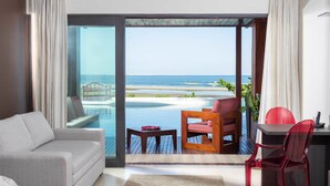 A modern room with a large sliding glass door leading to a beach view, a sofa, a wooden chair, and a small table. - Essenza Hotel (Jijoca de Jericoacoara)
