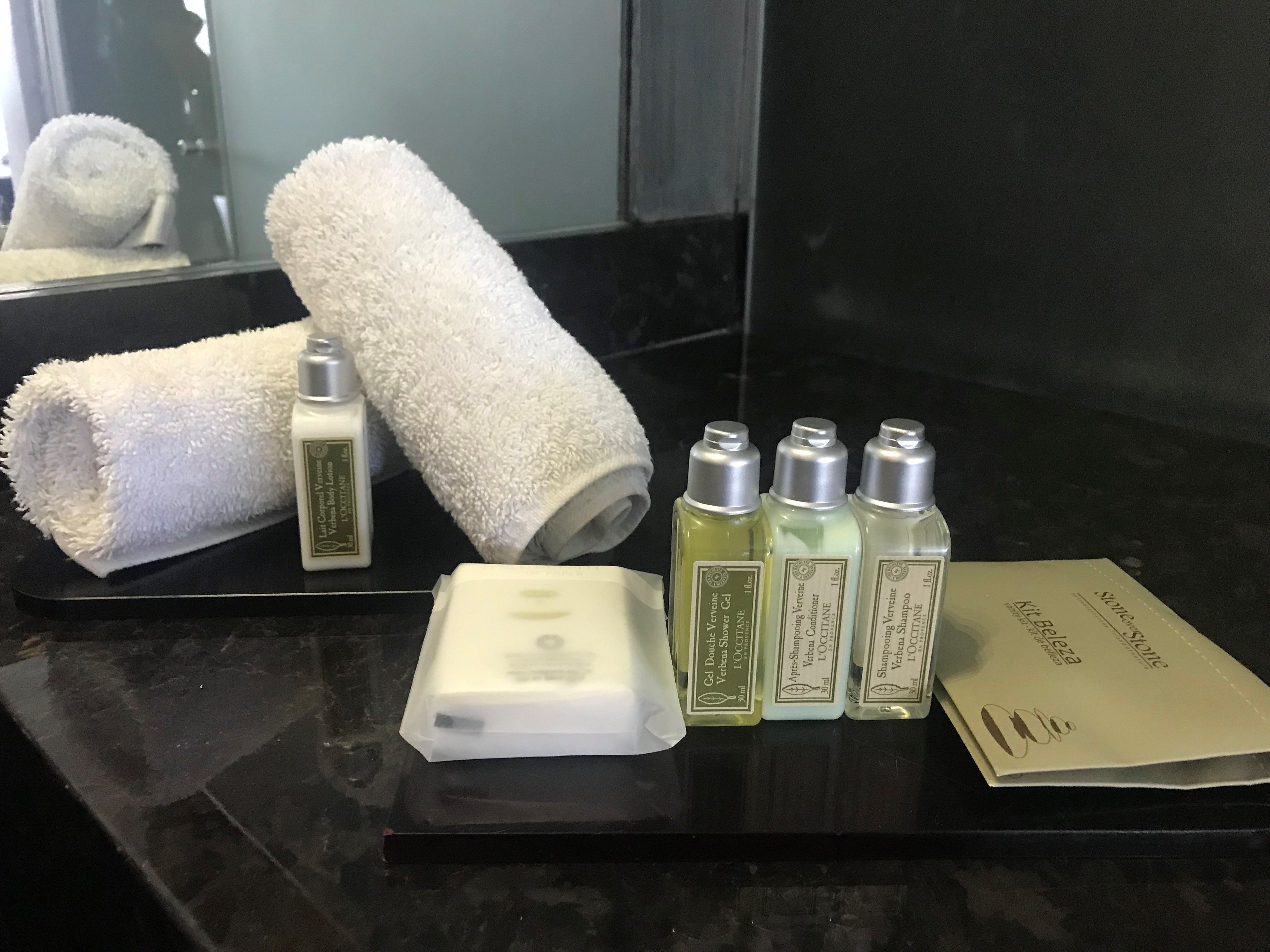 A bathroom counter with a towel, a bar of soap, and bottles of shampoo and conditioner.