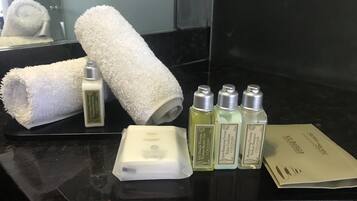A bathroom counter with a towel, a bar of soap, and bottles of shampoo and conditioner.