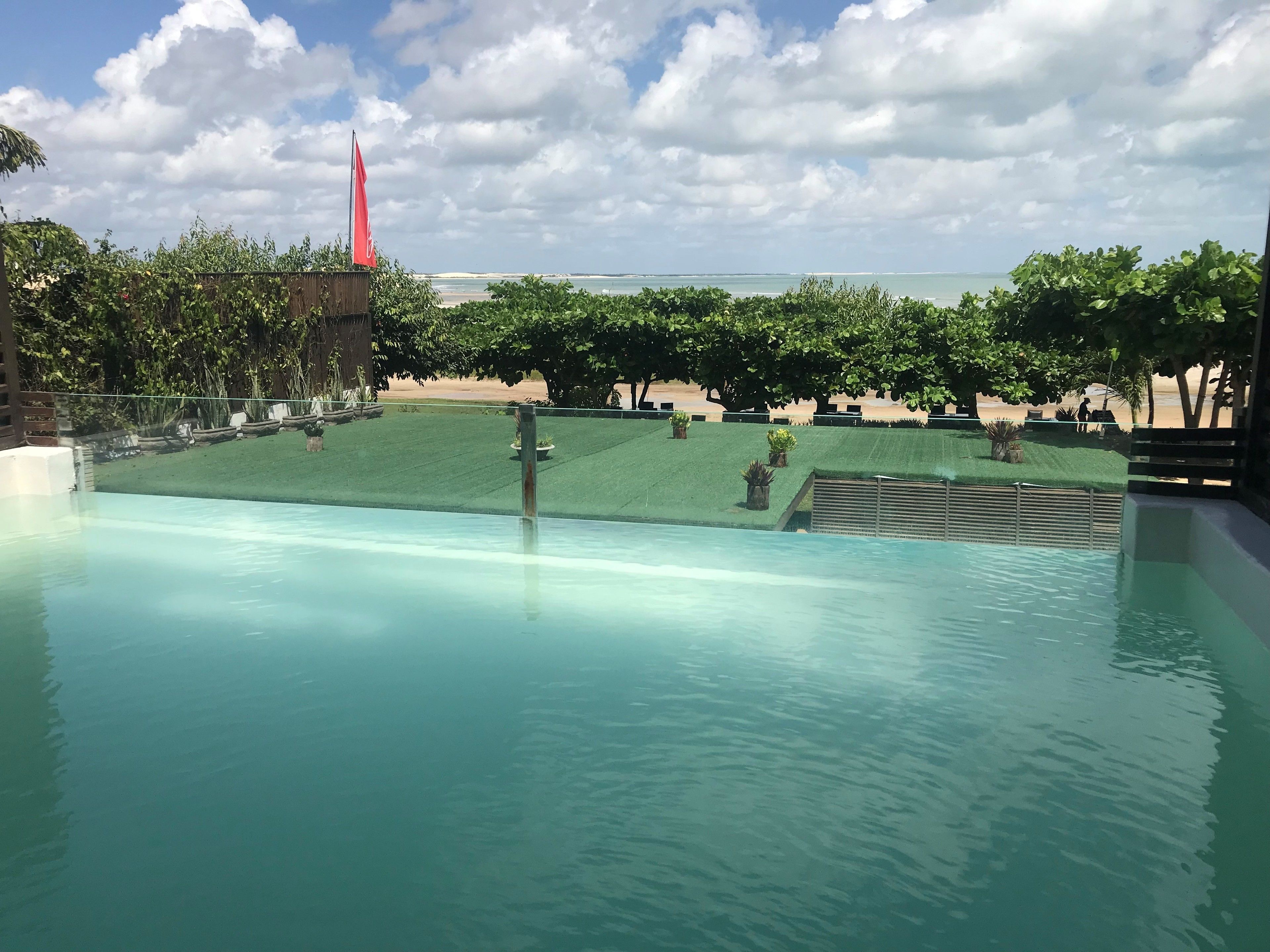 Une piscine avec vue sur une plage et, au loin, le clocher d’une église.