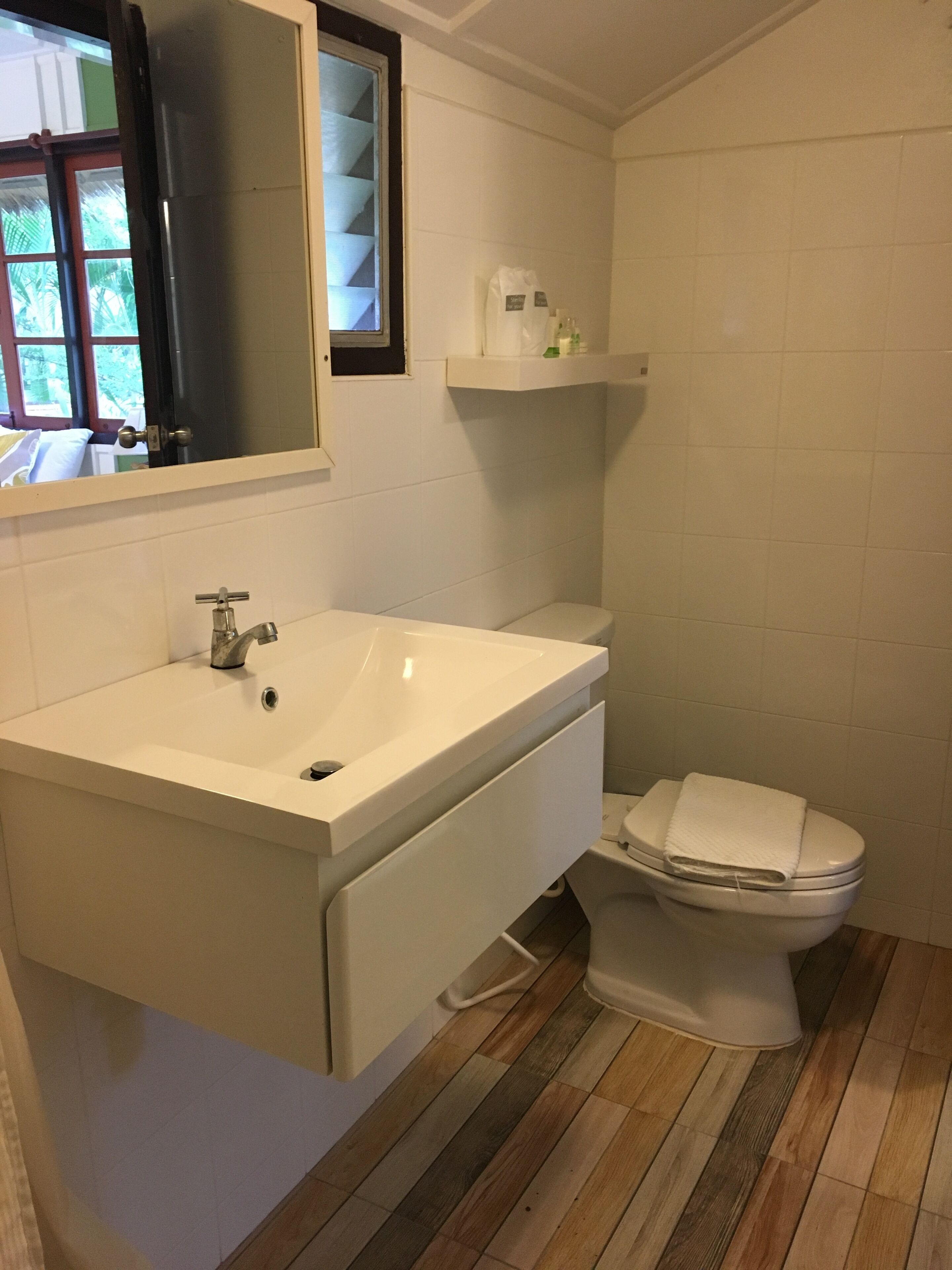 Un baño con lavamanos, espejo y retrete blancos.