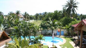 A pool area with a circular pool, lounge chairs, and palm trees.