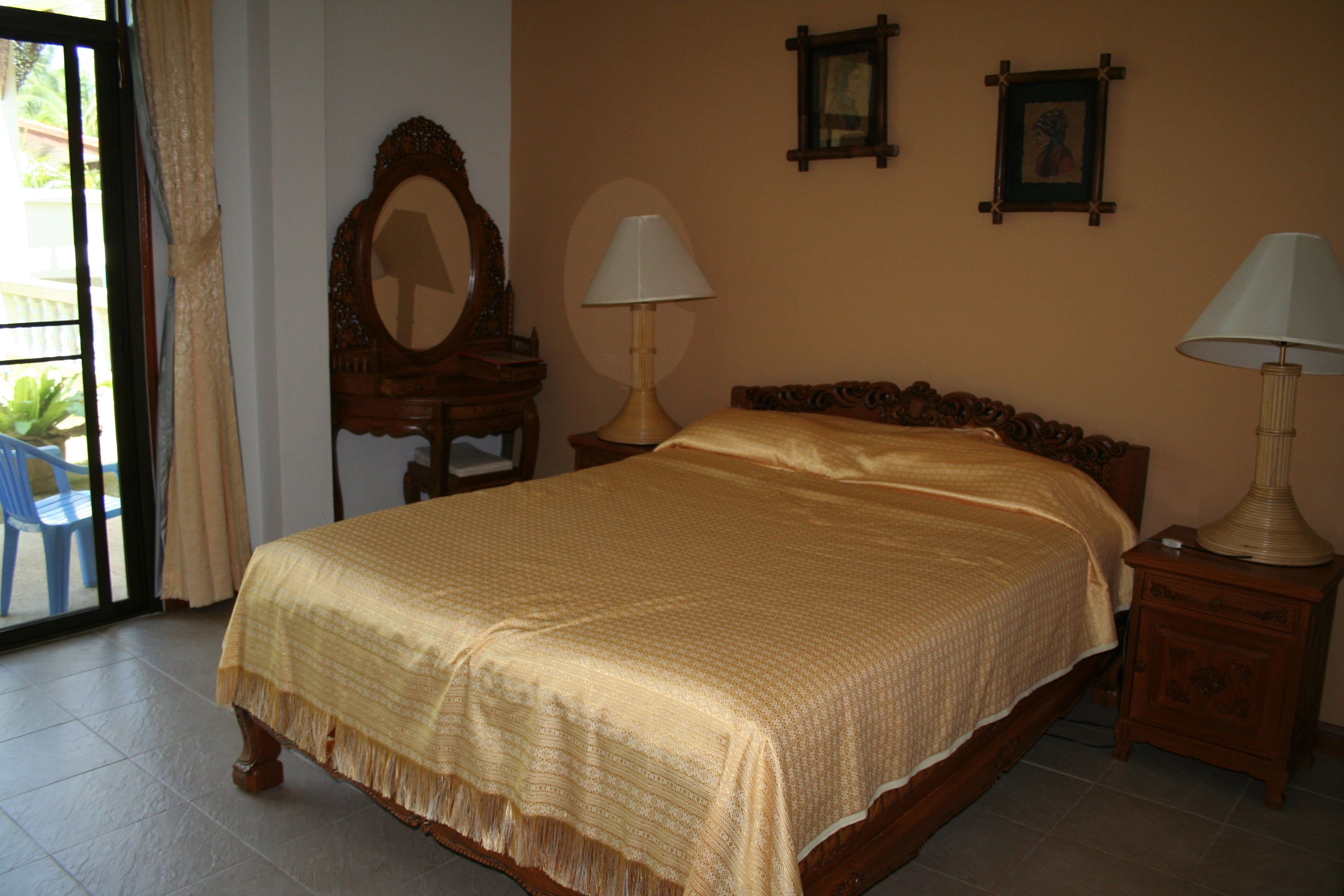 Un dormitorio con una cama grande, dos mesitas de noche con lámparas, un aparador de madera, un espejo y dos cuadros en la pared.