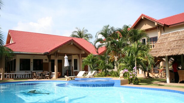 A swimming pool with lounge chairs and a covered seating area. - Long Beach Inn (Sam Roi Yot)