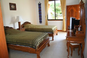 A room with two wooden beds, a wooden dresser, a mirror, and a window with curtains.