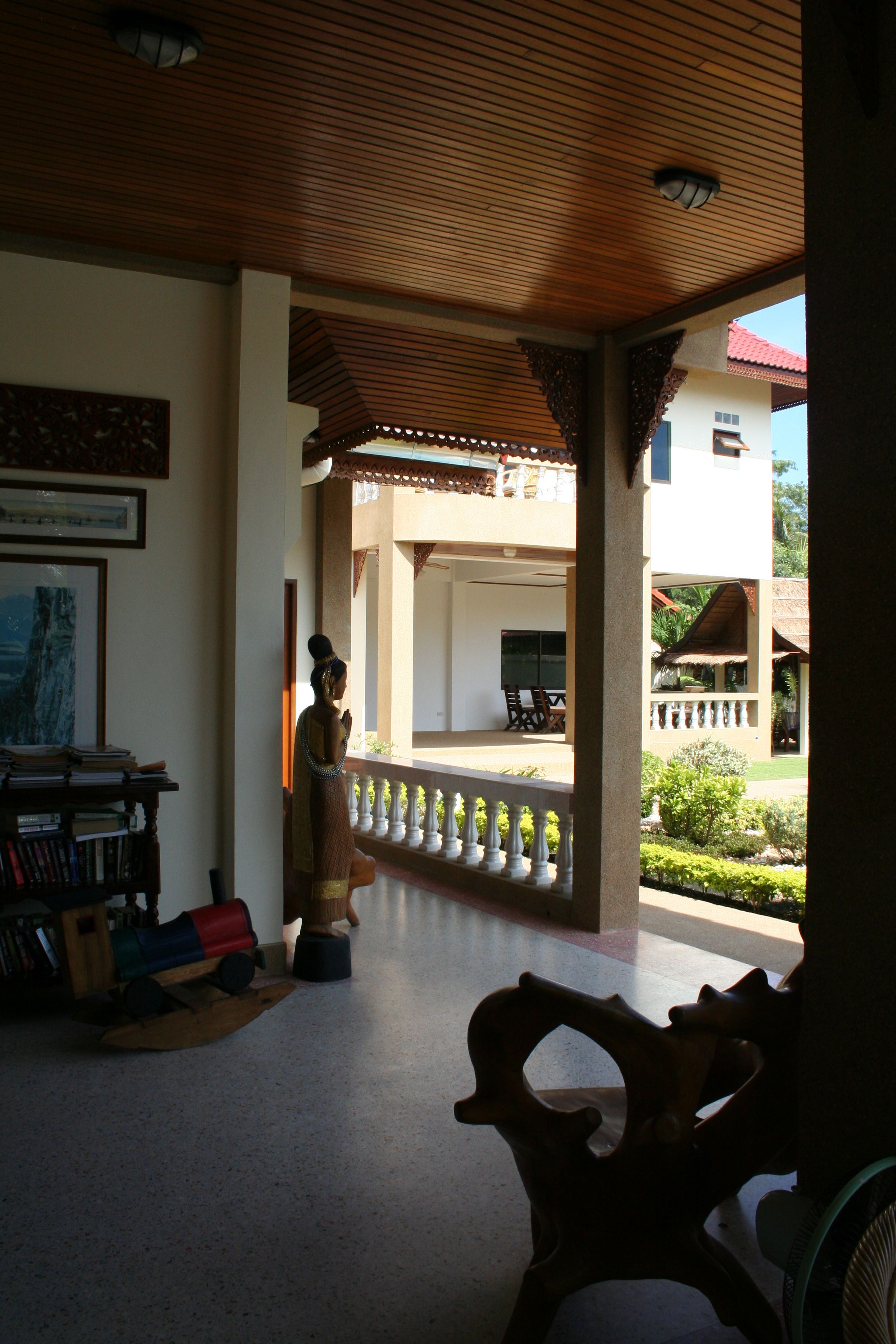 Una habitación con techo de madera, una estatua, una estantería y vistas a un edificio de tejado rojo.