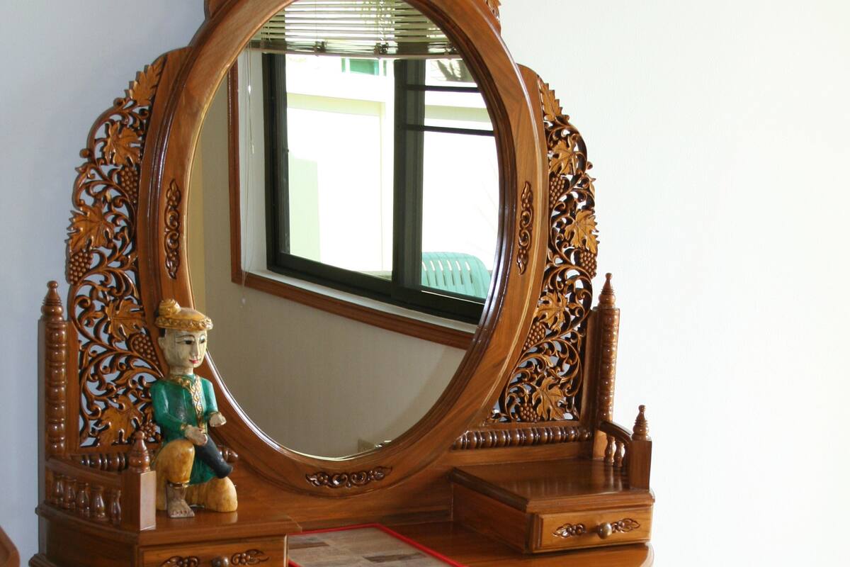 A wooden vanity with a large mirror, a small statue, and a red book.