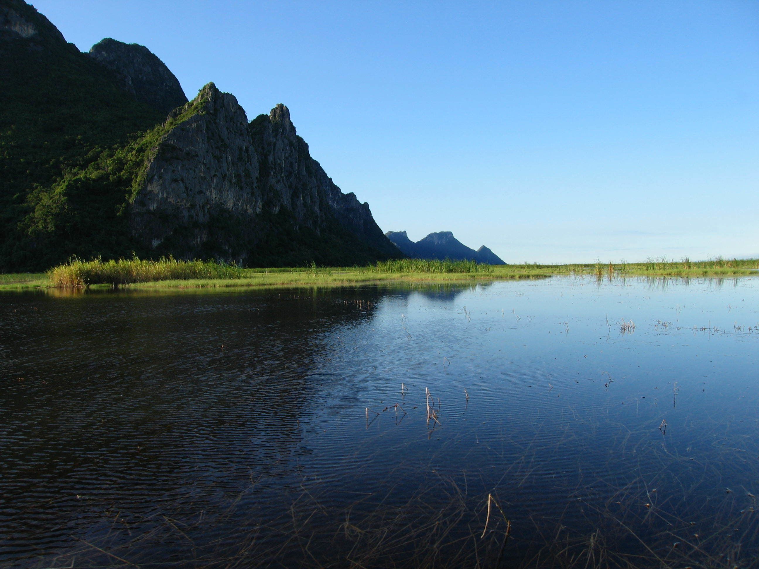 A calm lake with a rocky mountain in the background.