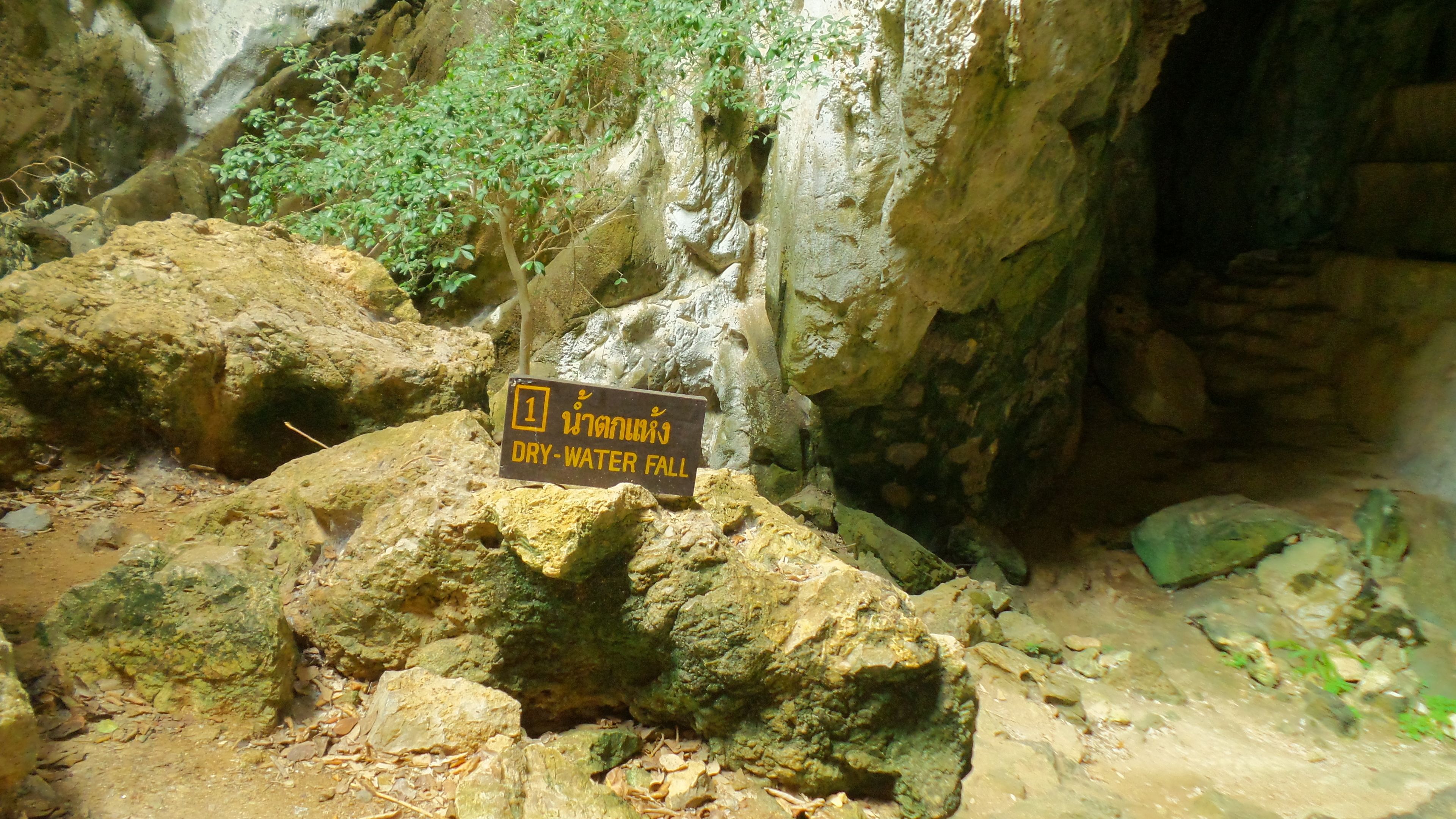 Boca de cueva con un cartel que indica una cascada seca.