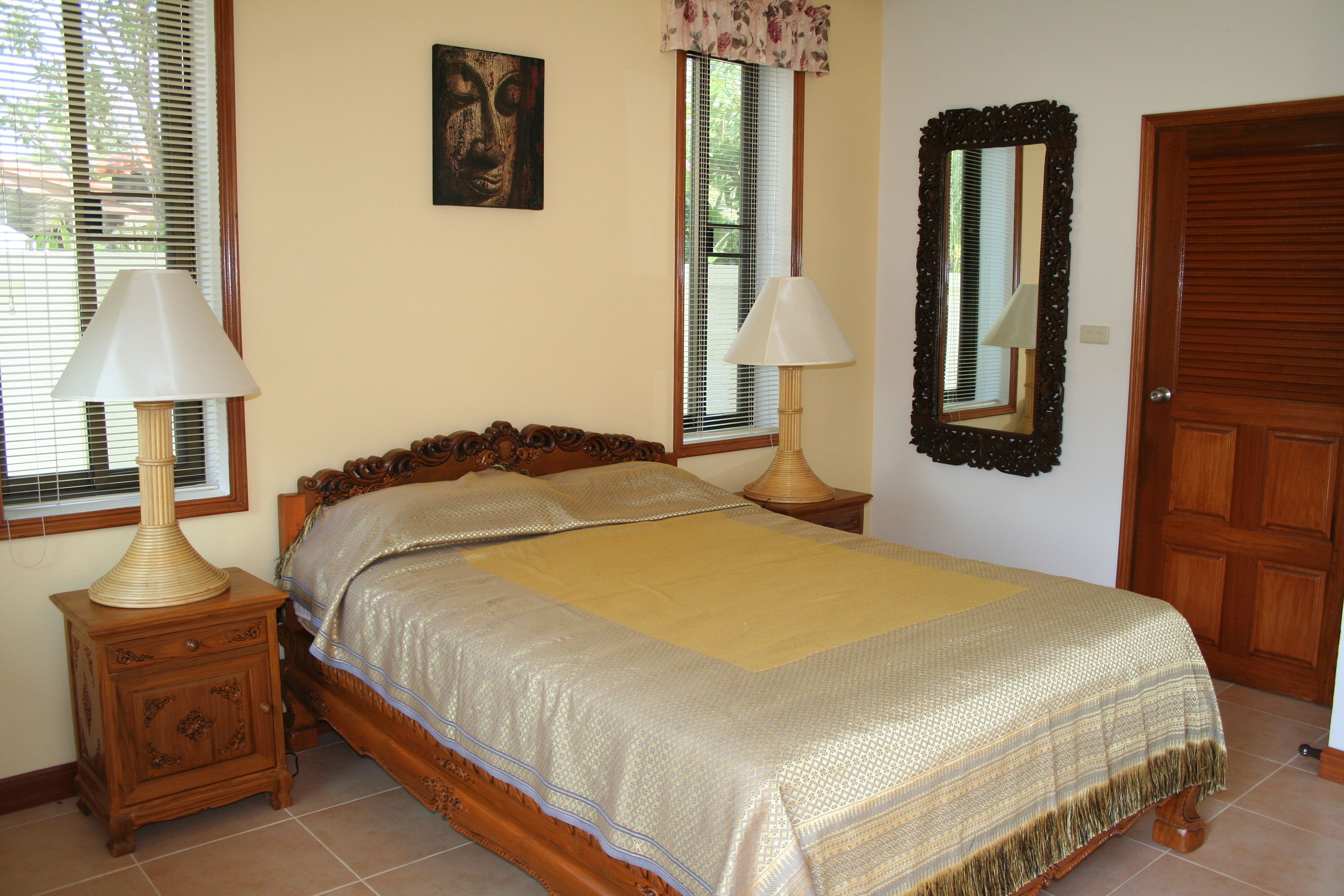 Un dormitorio con una cama, dos mesitas de noche, un espejo y una puerta.