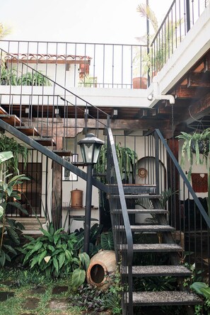 Una escalera exterior de varios niveles rodeada de abundante vegetación y plantas en macetas.