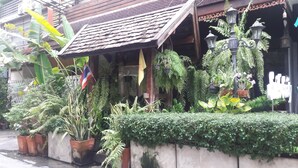 A traditional building with a tiled roof, potted plants, and a flag. - Smile Society Boutique Hostel (Bangkok)