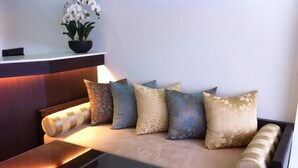 A sofa with multiple cushions, a small table, and a potted plant. - Smile Society Boutique Hostel (Bangkok)