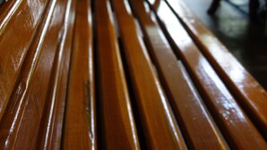 A wooden bench with a metal frame, accompanied by a potted plant and a table with chairs. - Smile Society Boutique Hostel (Bangkok)