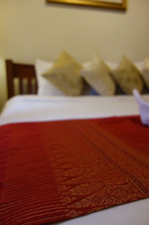 A bed with a red blanket and pillows.