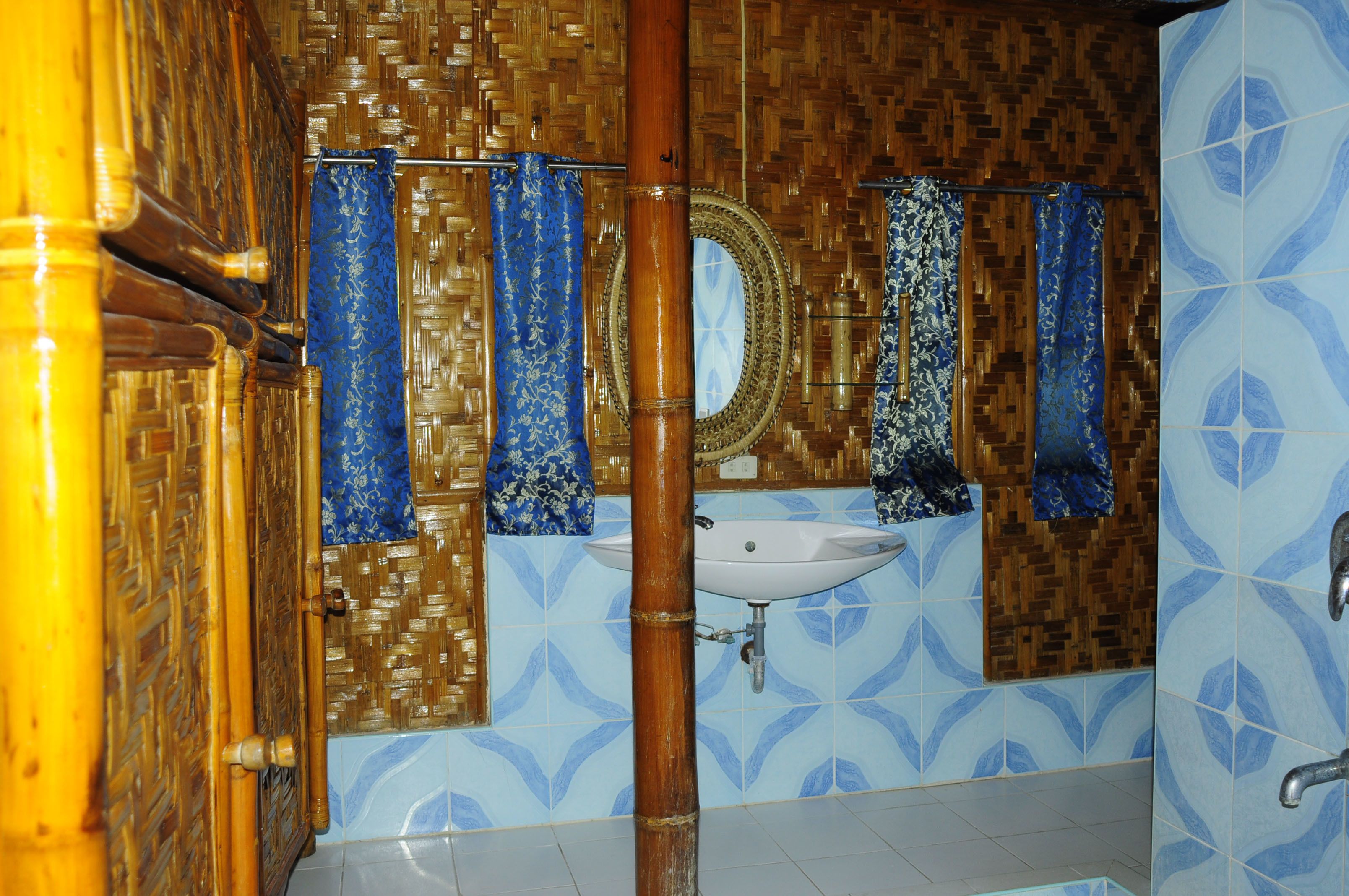 A bathroom with a bamboo door, a sink, and patterned blue and brown tiles.