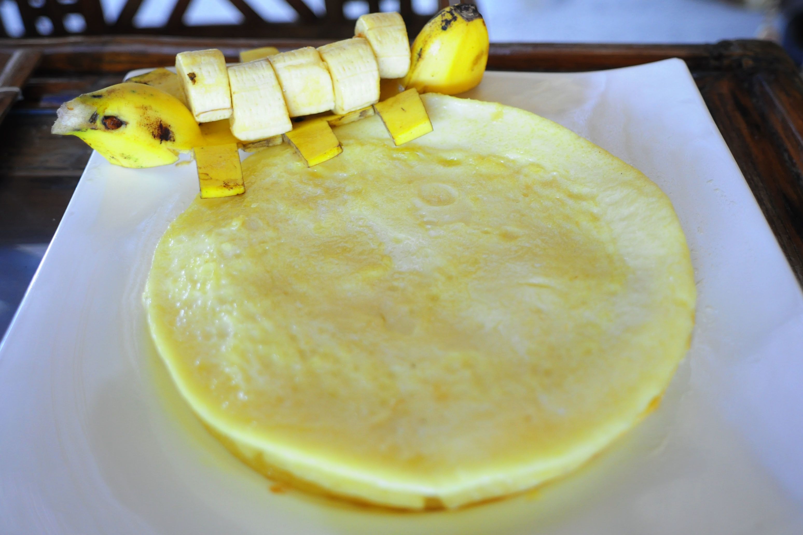 Ein Teller mit einem Pfannkuchen und Bananenscheiben.