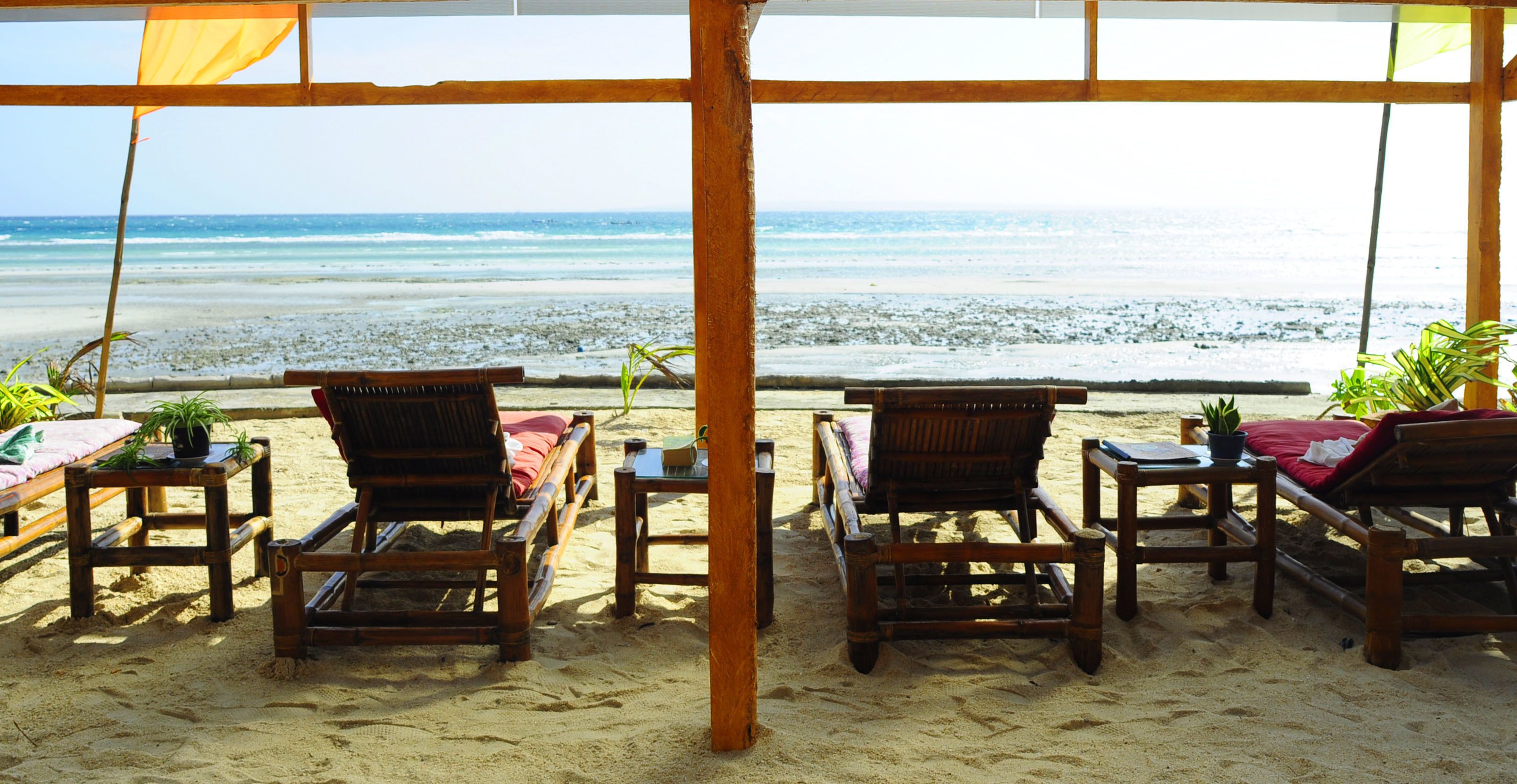 Un área de descanso frente a la playa con muebles de madera y vista al océano.