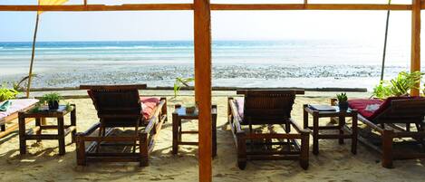 Un área de descanso frente a la playa con muebles de madera y vista al océano.