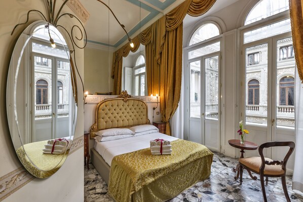 A hotel room with a large bed, a sitting area with a chair, a small table, and a large mirror. - B&B Art Suite Santa Brigida (Naples)