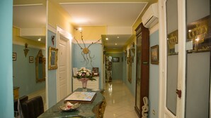 A hallway with a dining area featuring a marble table, chairs, and a vase with flowers. - B&B Art Suite Santa Brigida (Naples)