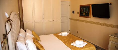 Una habitación de hotel con una cama, un armario, un televisor y un teléfono sobre la mesita de noche.