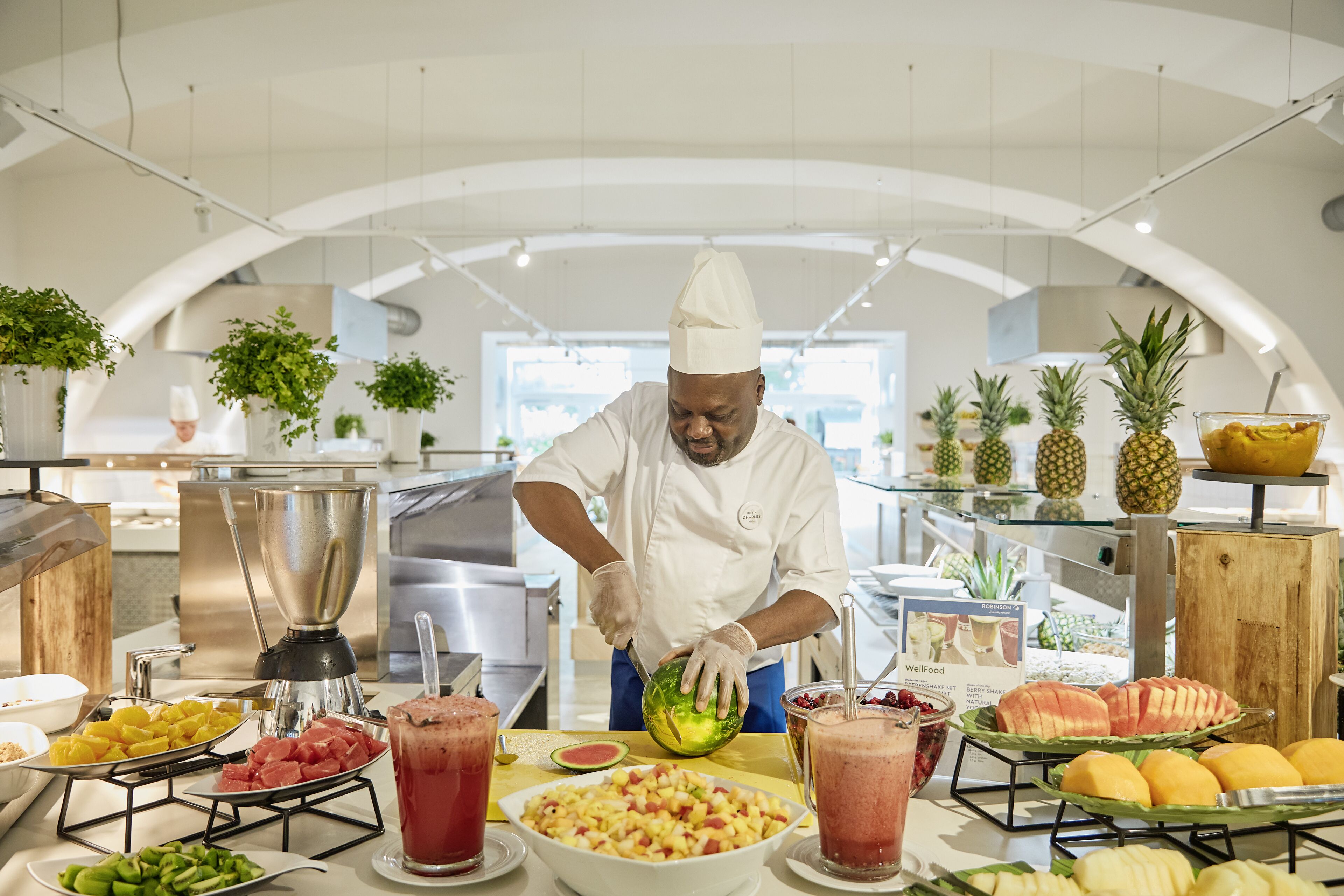 A buffet setup with various fruits and a chef preparing food.