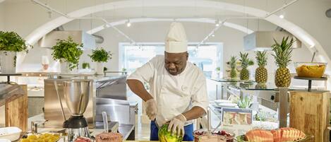 A buffet setup with various fruits and a chef preparing food.