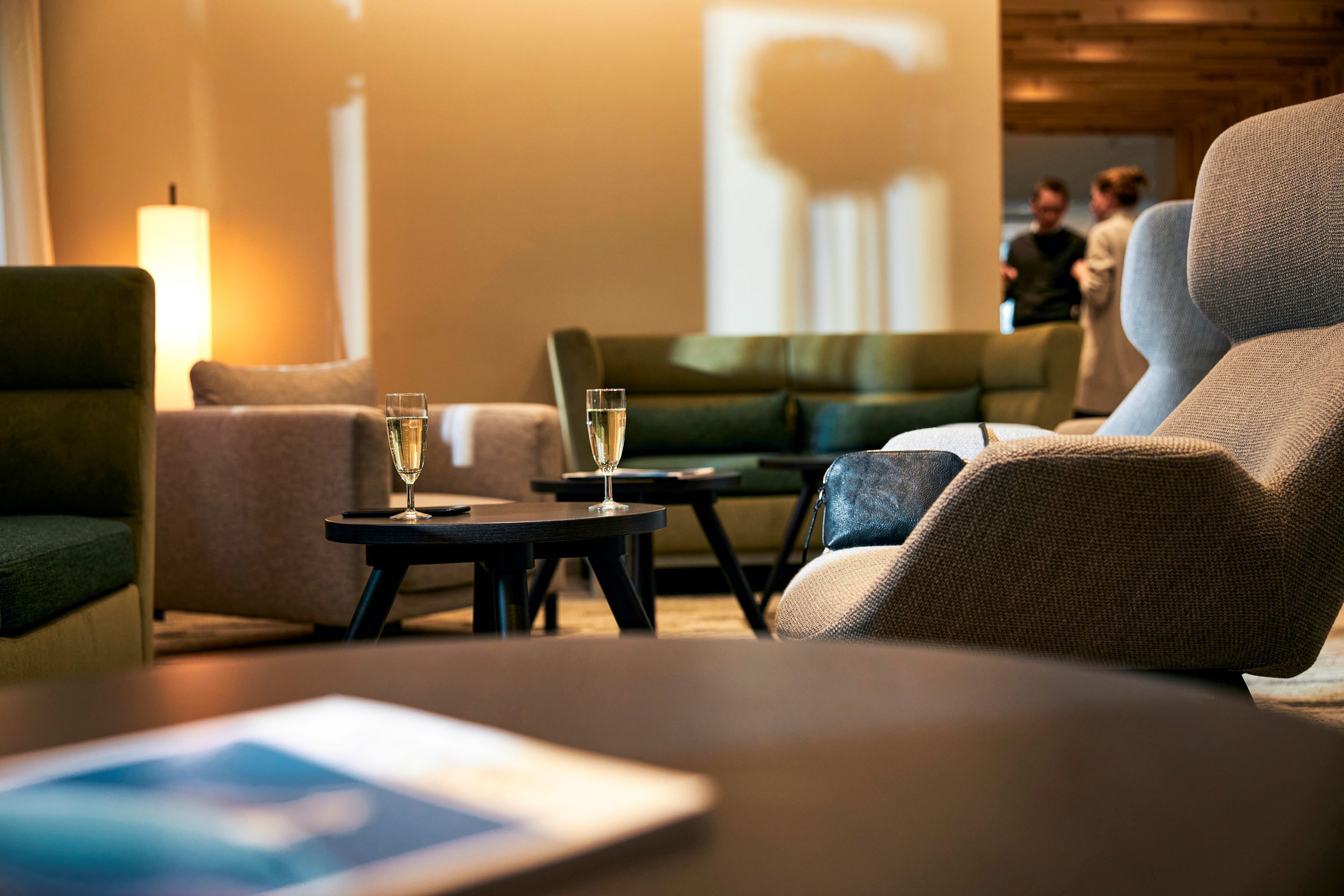 Une chambre d’hôtel moderne équipée d’un canapé, de fauteuils, d’une petite table avec des verres et d’une tablette.