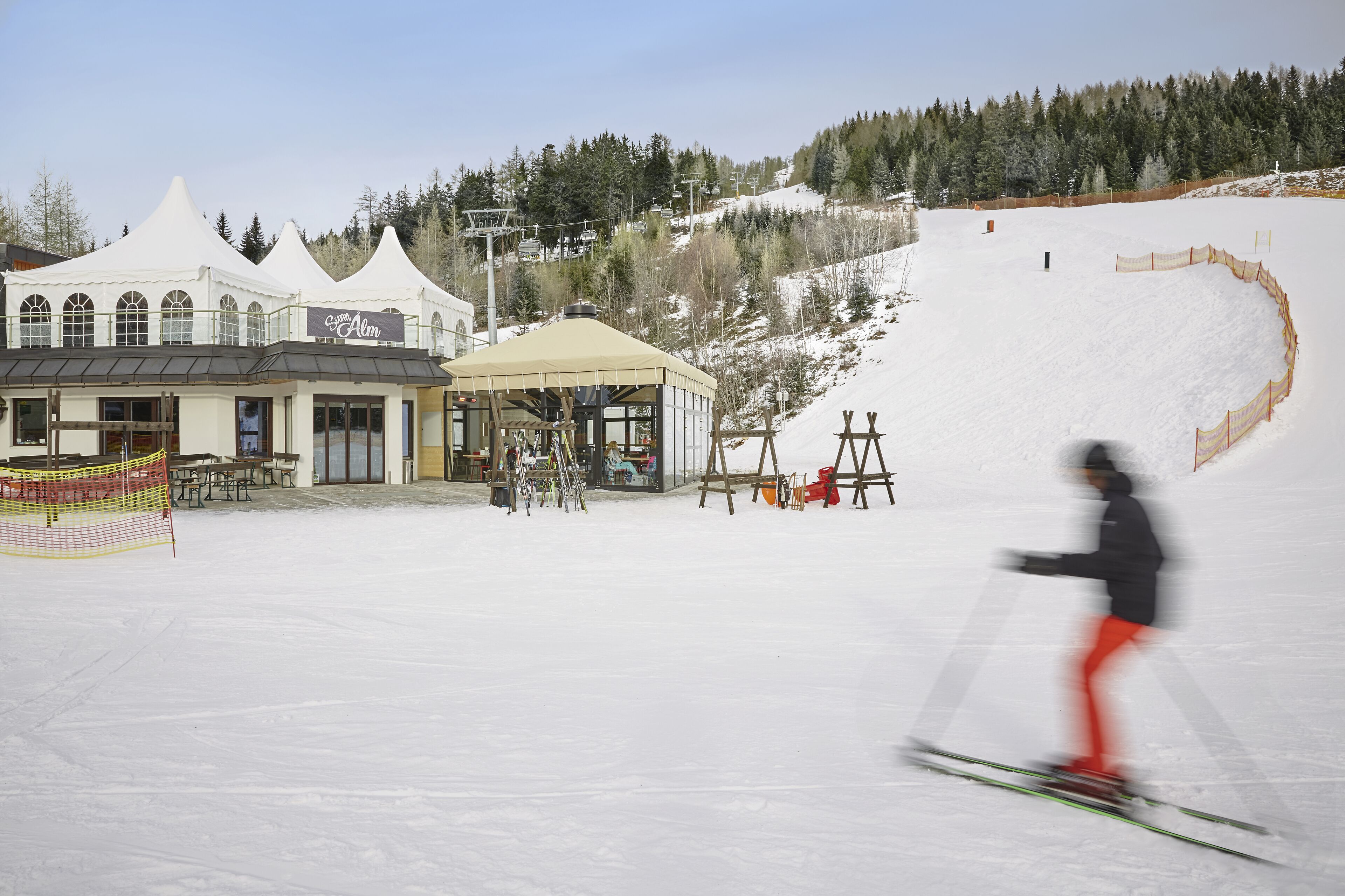 Una stazione sciistica con un'area coperta, un edificio con un cartello e una pista innevata.
