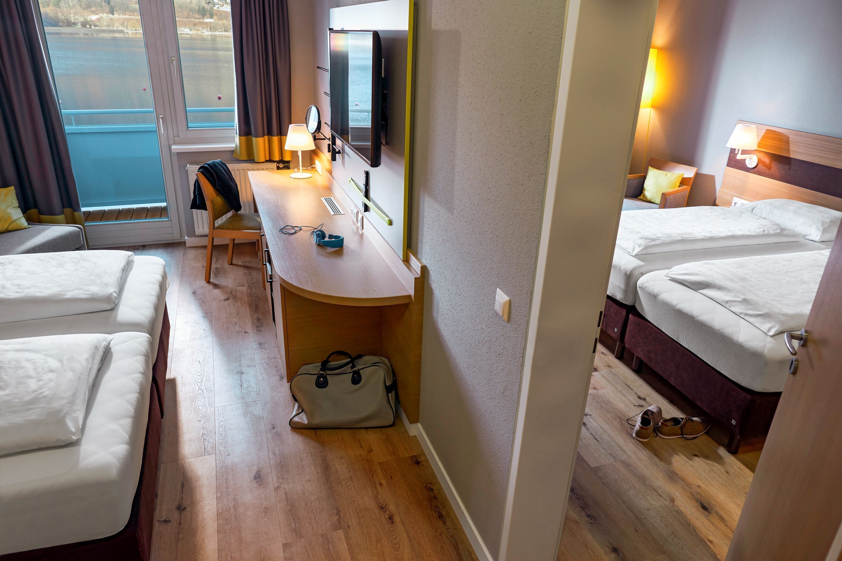 Een hotelkamer met twee bedden, een bureau met stoel, een tas en een televisie.