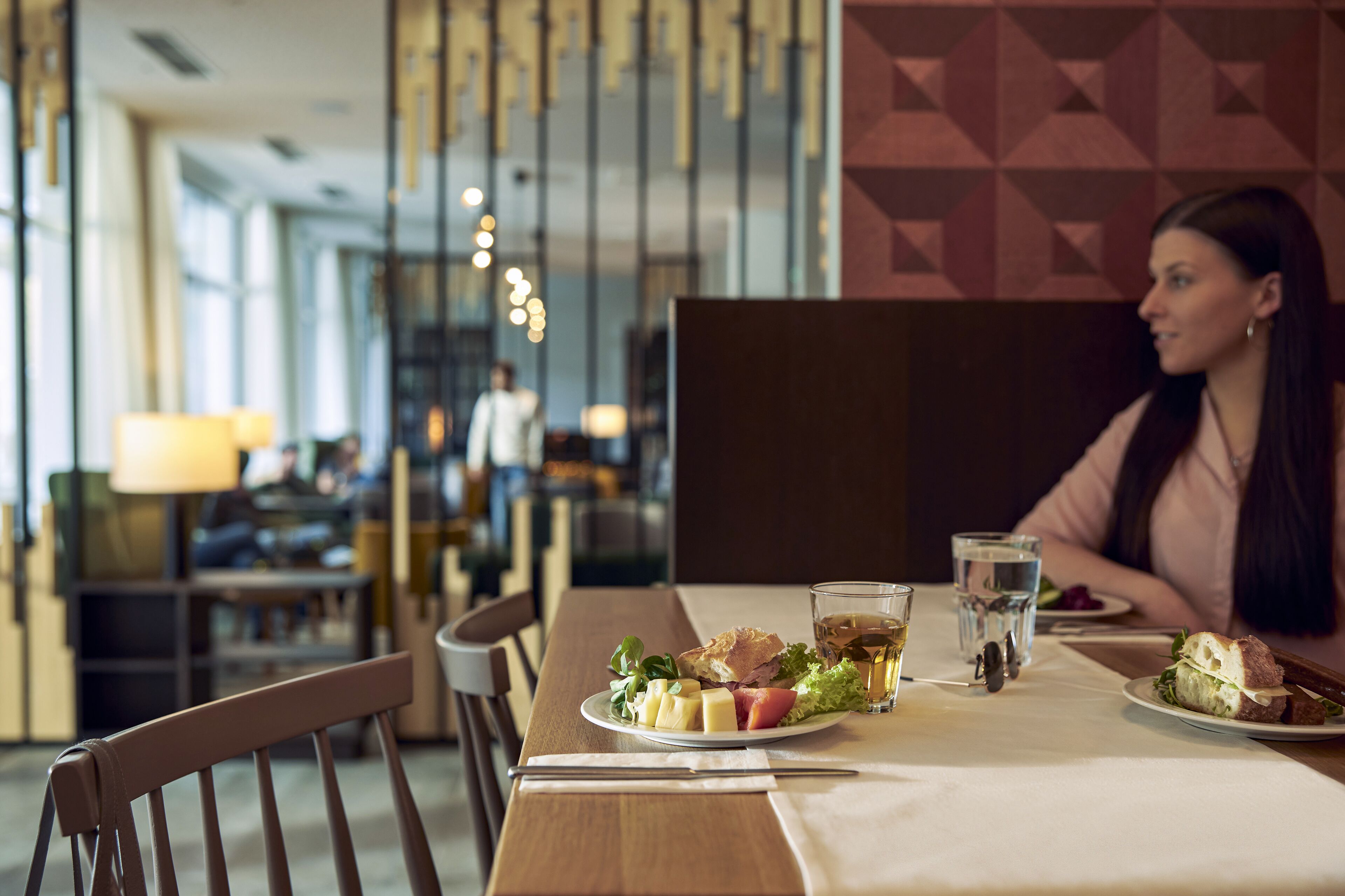 A dining table with a plate of food, a glass of water, and a sandwich.