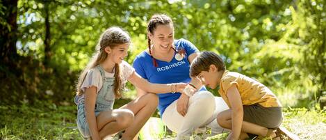 A family of three outdoors in a lush, green environment.