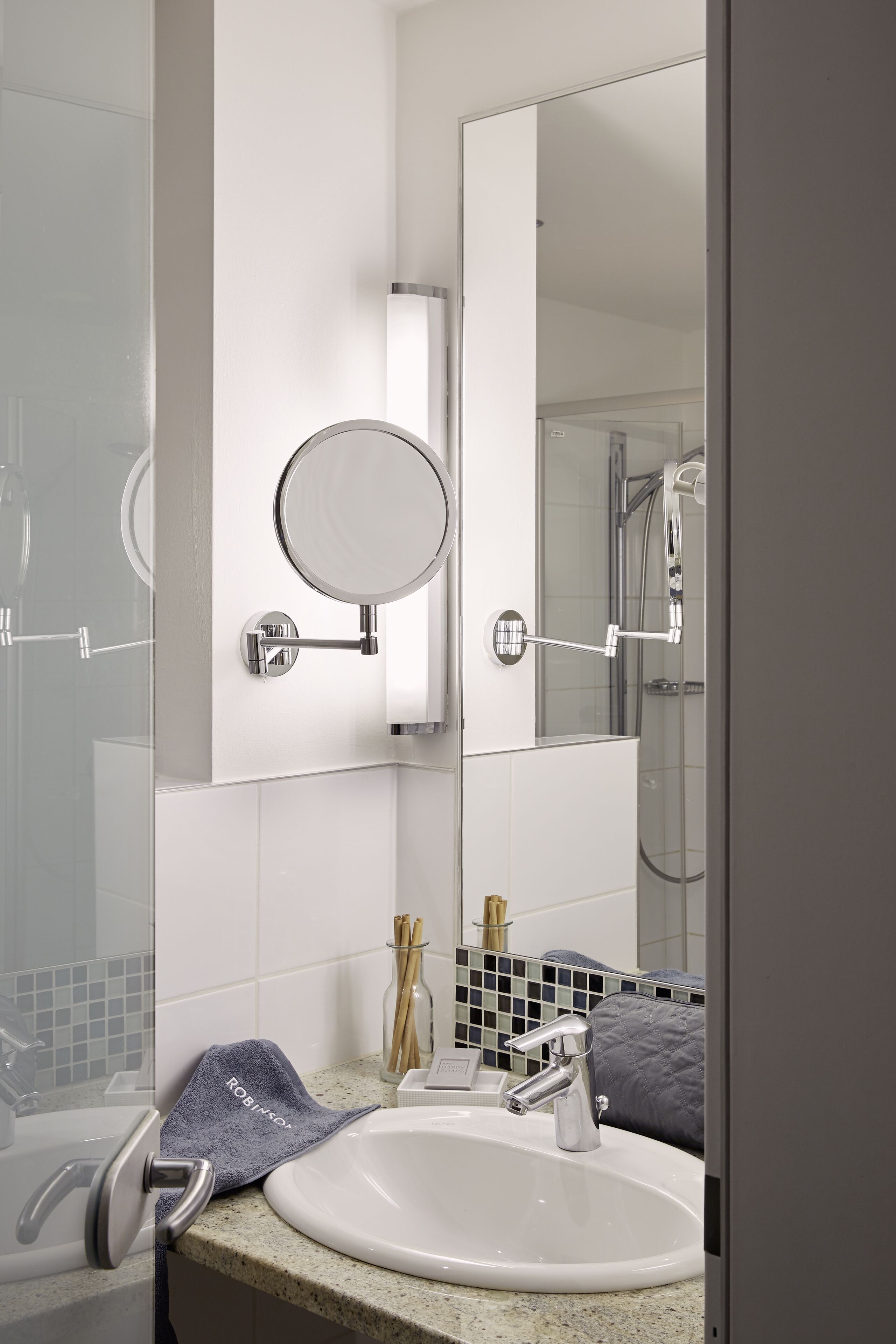 A bathroom with a white sink, a round mirror, and a shower.
