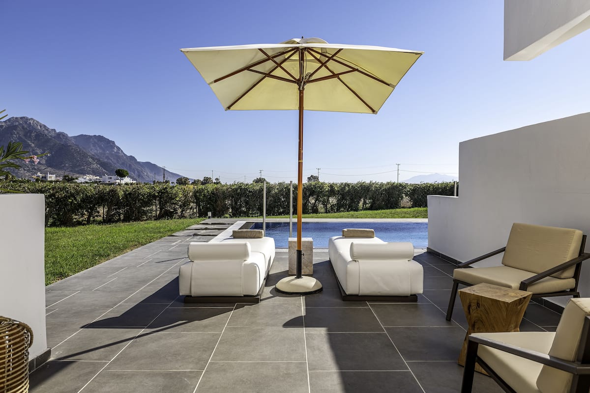 A patio with white sofas, a wooden coffee table, and a large umbrella.