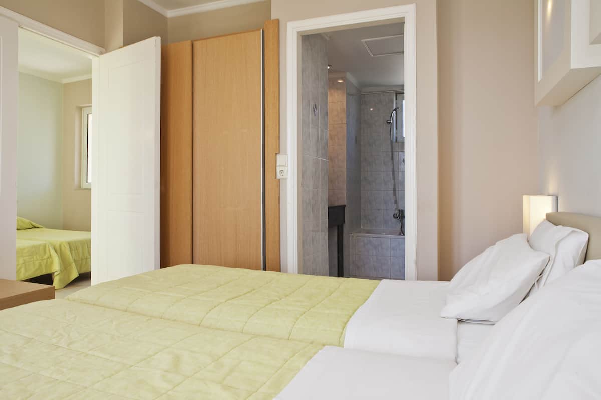 A hotel room with a bed, a wooden wardrobe, and a bathroom visible through an open door.