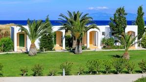 A coastal hotel with white architecture, palm trees, and a view of the sea.
