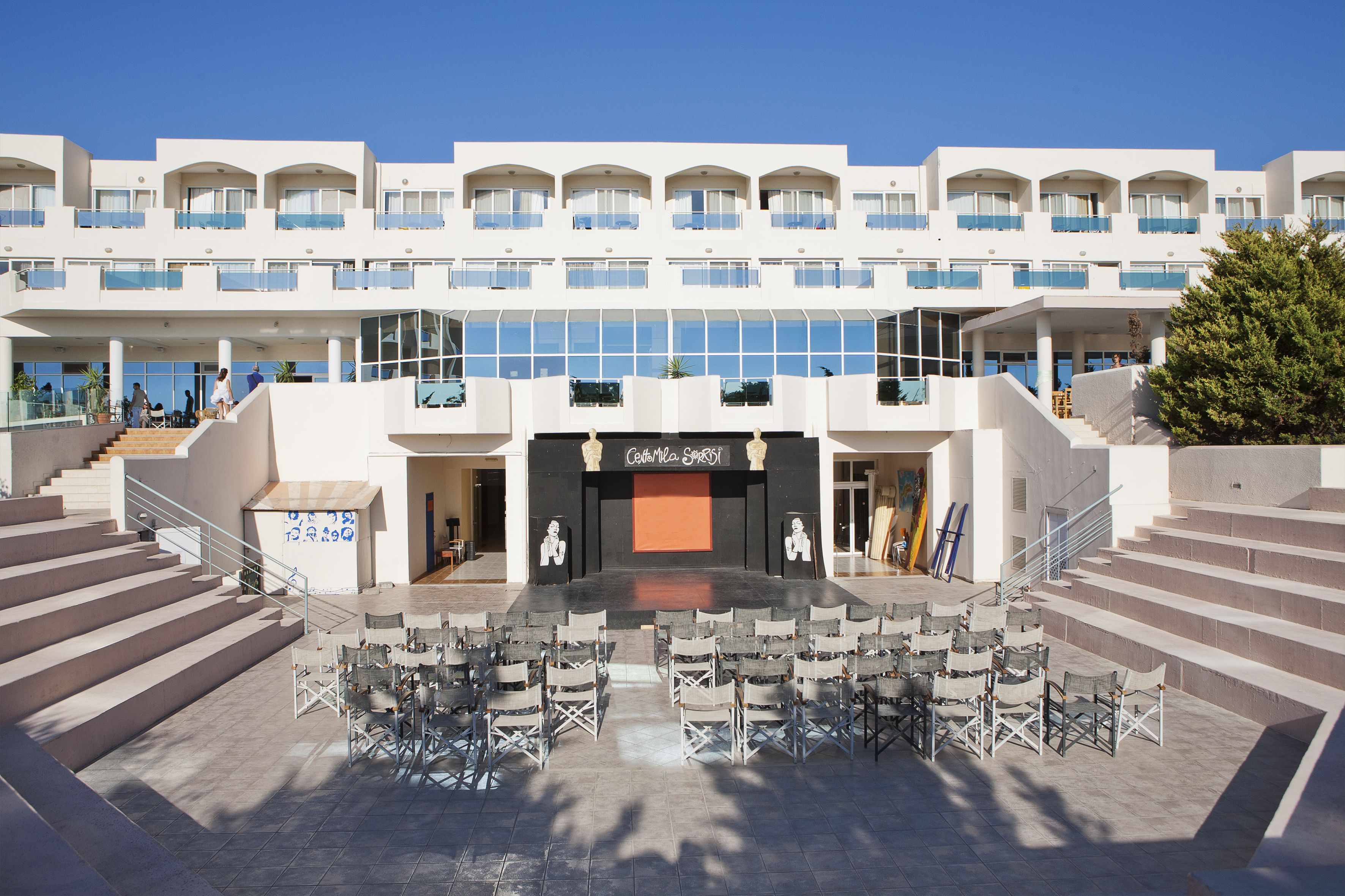 Hotel moderno com pátio central, área de estar ao ar livre e várias varandas.