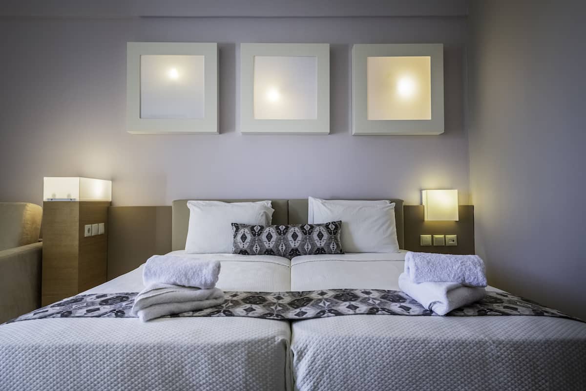 A hotel room with a double bed, two bedside tables, and three wall-mounted lights.